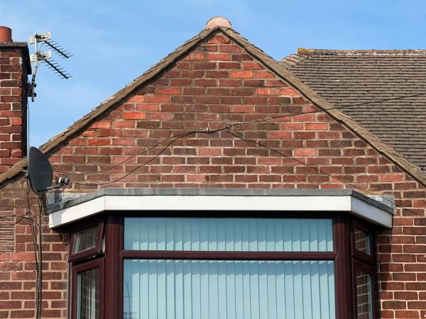 Repointed gable end brickwork rising to the finial above the bay window