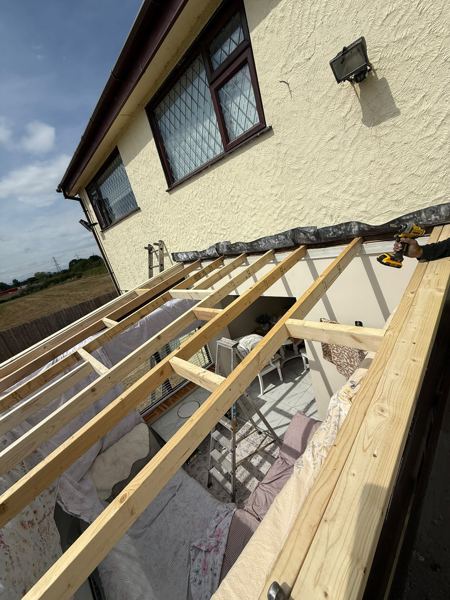 New timber rafters over the conservatory frame, furniture covered below