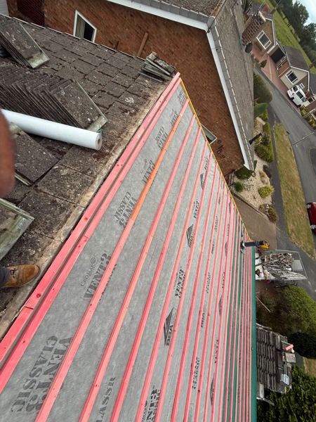 Grey breathable membrane and new battens beside old concrete tiles