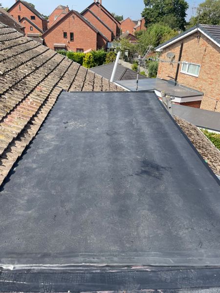 Finished EPDM rubber roof running between two concrete-tiled pitched roofs