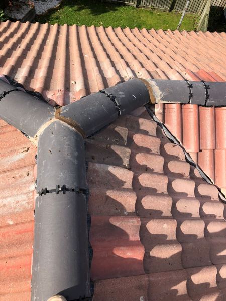 Three-way ridge junction in charcoal tiles, each joint held by clips