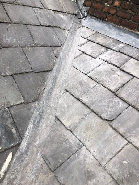 Finished lead valley with slates relaid and flashing against the brick parapet