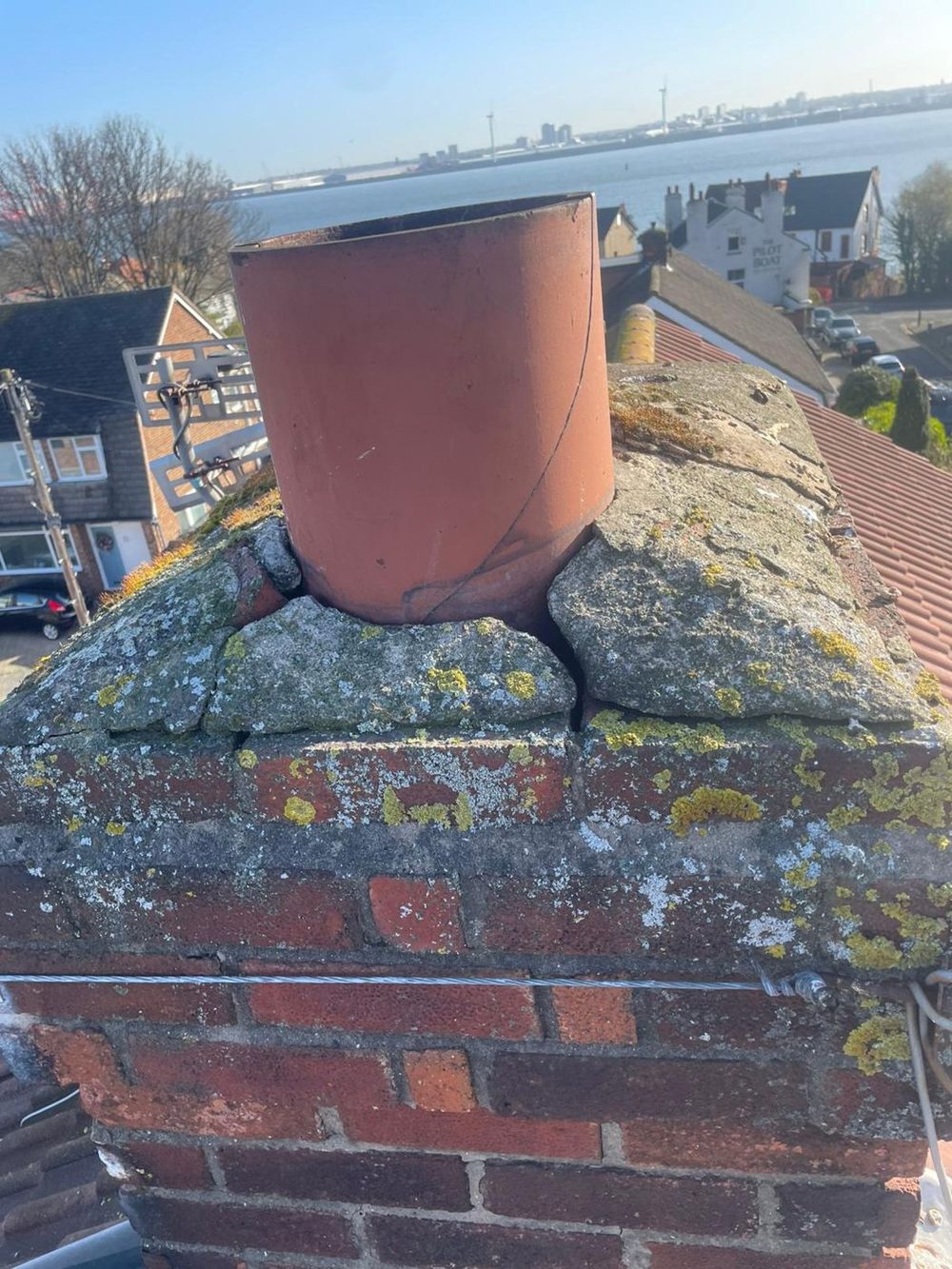 Flaunching cracked into loose pieces and a split pot on a weathered brick stack