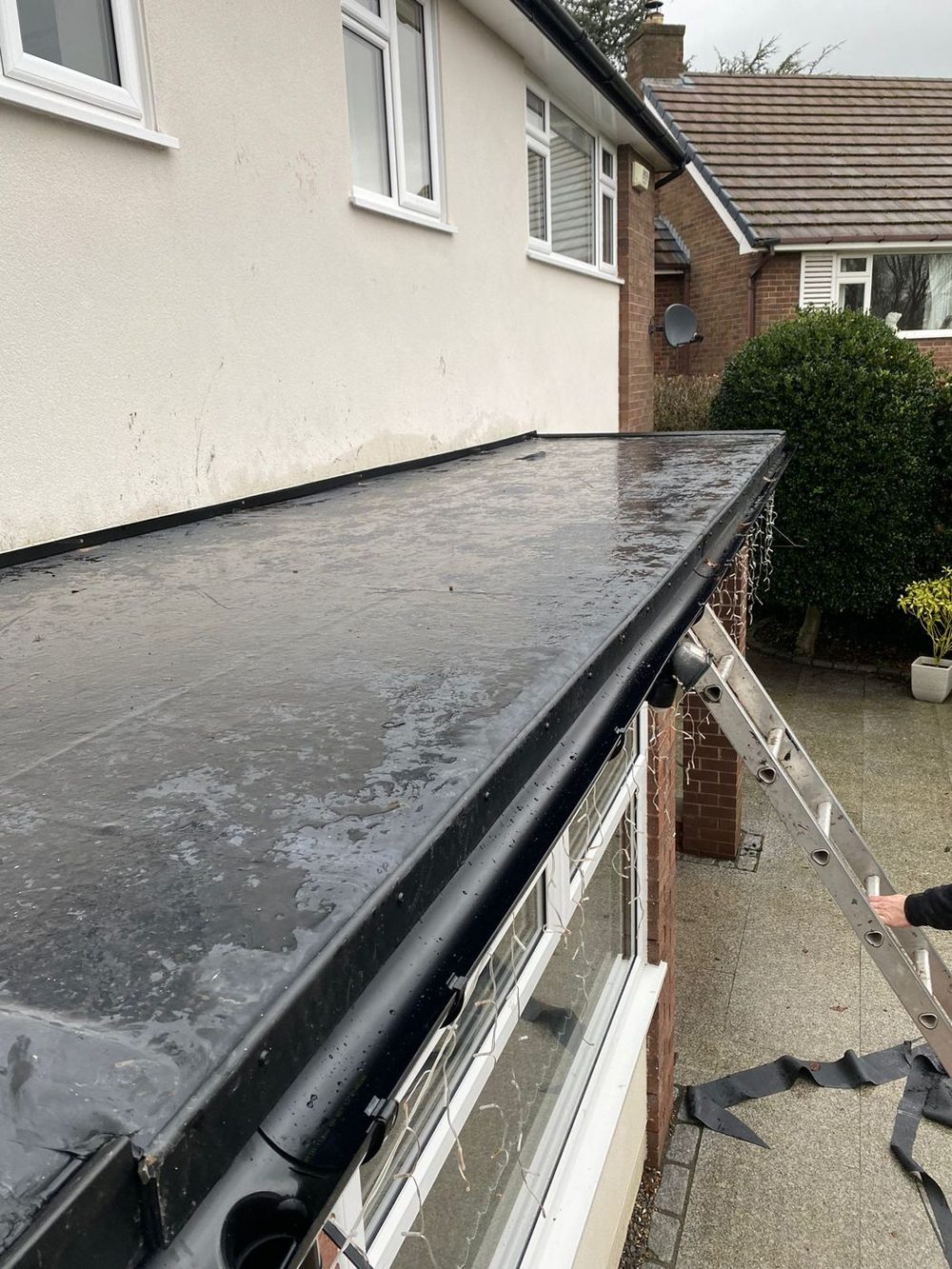 A finished roof seen from the top of the ladder, the covering turned over the trim into the gutter along the front