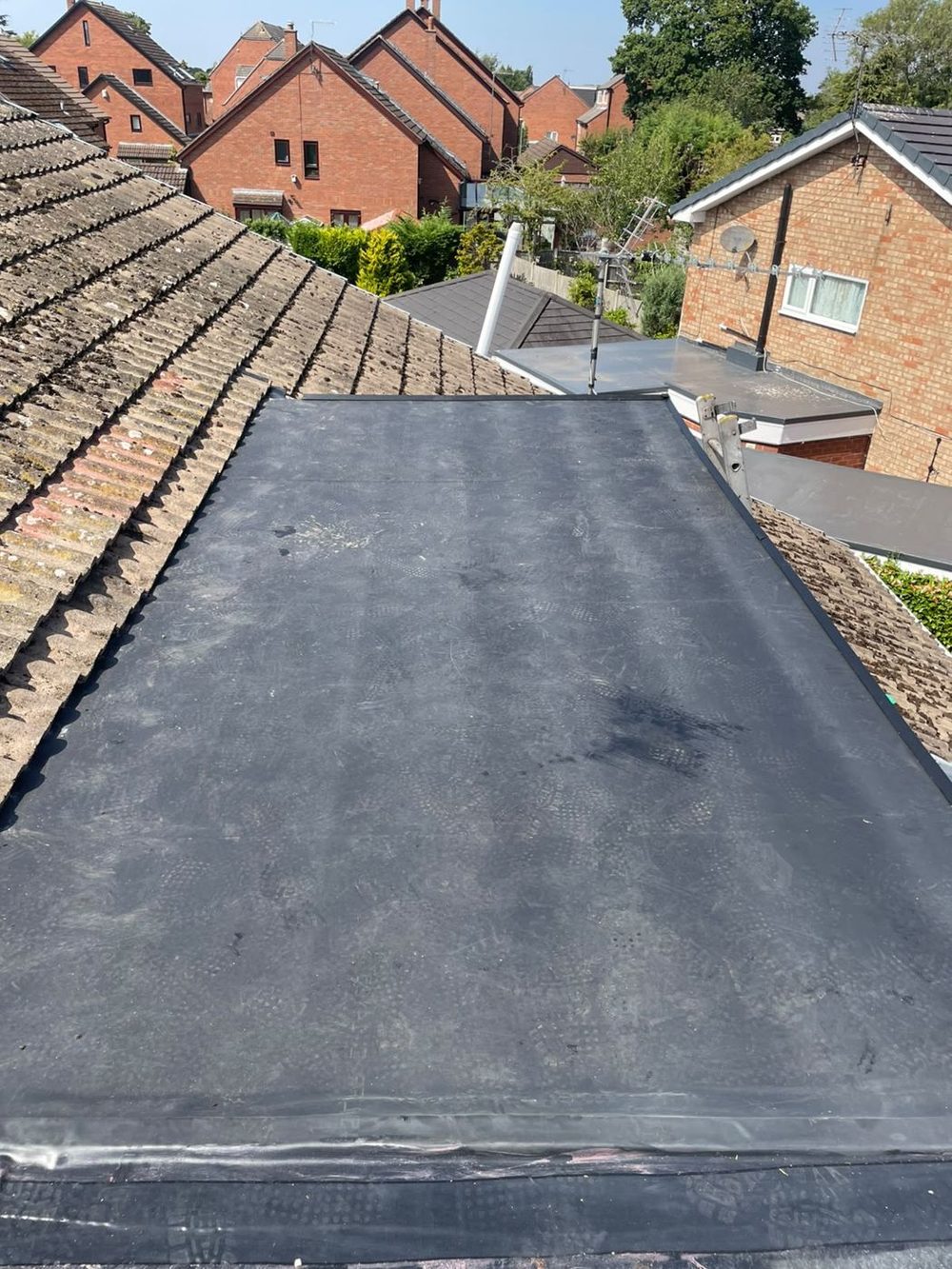 A finished flat roof set between two tiled slopes, seen out over the neighbouring rooftops