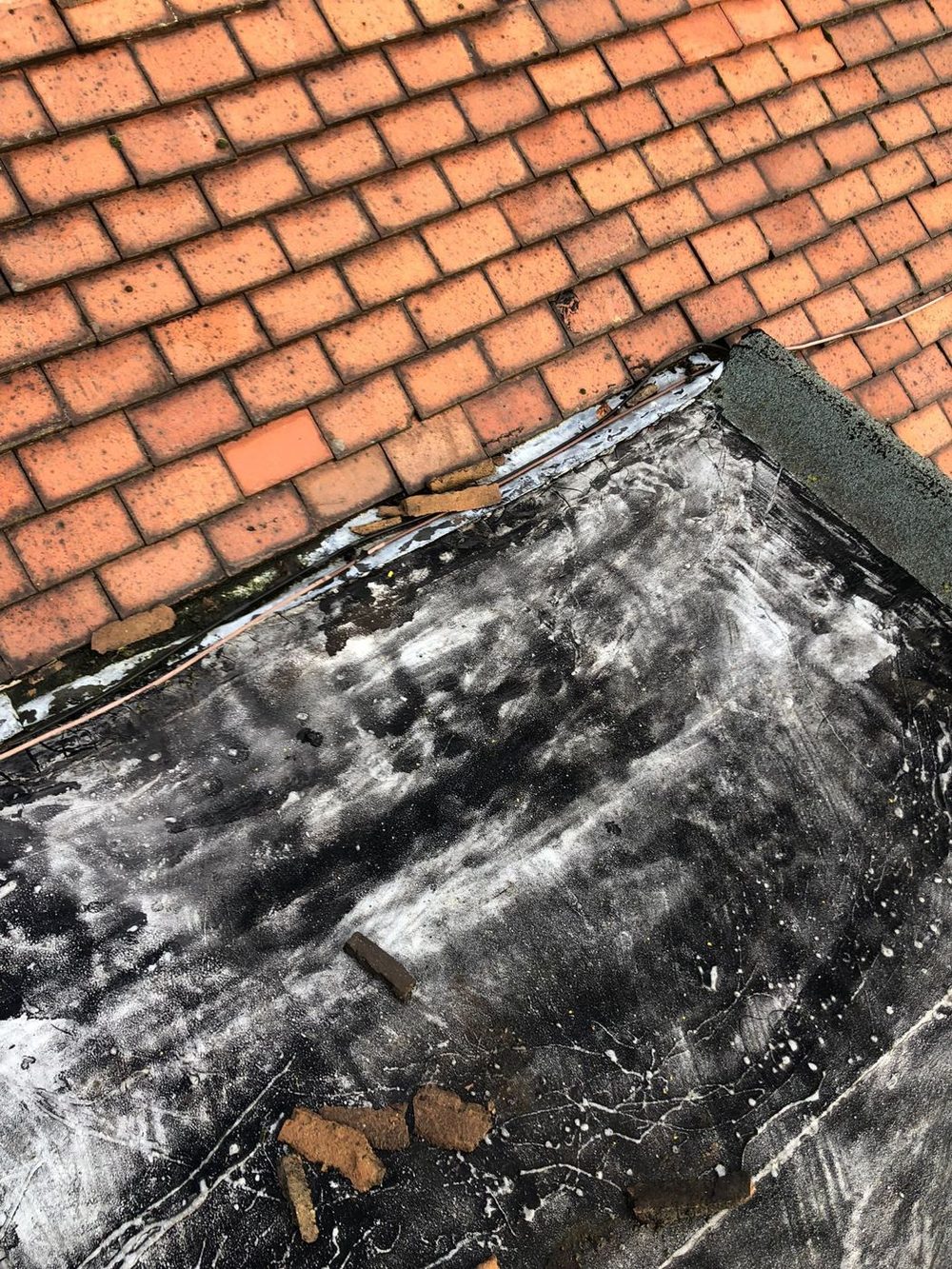 Felt at the end of its life against a brick wall, the mineral surface gone and the edge open