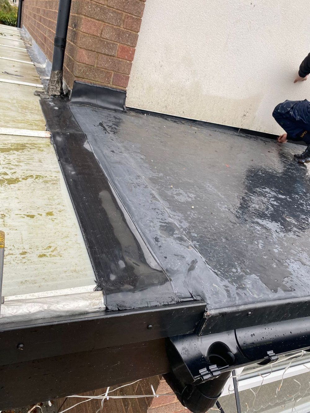 The covering taken over the edge and dressed down into a new gutter, with the downpipe fitted below it