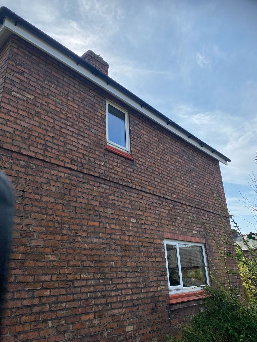 New white UPVC fascia, soffit and black guttering on a brick gable in Helsby